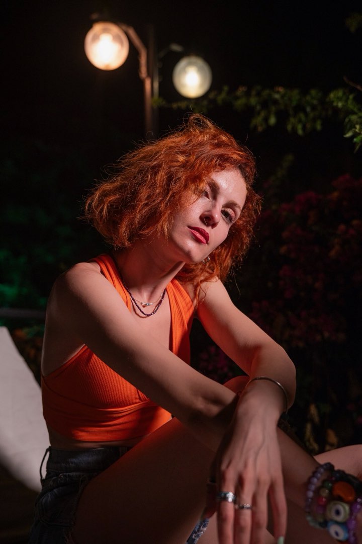 Portrait in an orange top under warm garden lights at night
