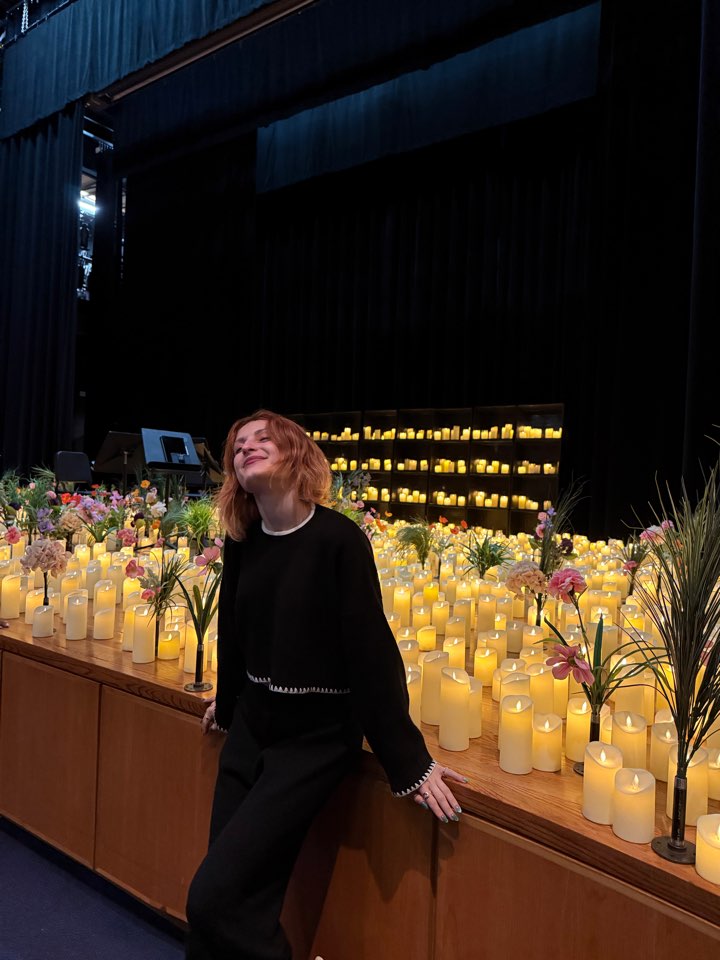 Smiling in front of a stage filled with glowing candles and flowers